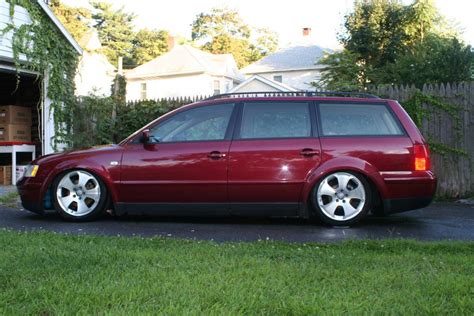 A Red Station Wagon Parked In Front Of A House On The Side Of A Road