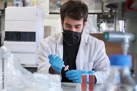 Scientist In White Lab Coat And Protective Face Mask Filter Sample Into