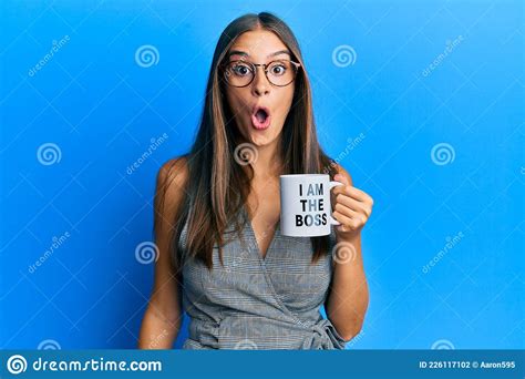 Young Hispanic Woman Drinking From I Am The Boss Coffee Cup Scared And