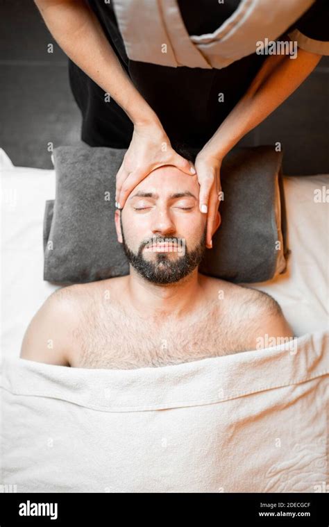 Bearded Man Receiving A Facial Massage Relaxing At Spa Salon View