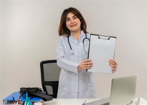 Sonriente doctora de mediana edad vistiendo bata médica y estetoscopio