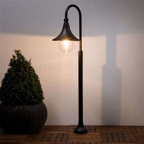 A Lamp On A Wooden Floor Next To A Potted Plant