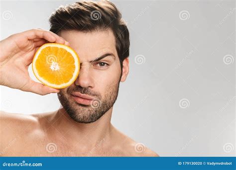 Photo Of Handsome Half Naked Man Looking At Camera And Holding Orange