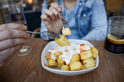 Lesbian Couple Sharing Patatas Bravas With Alioli And Vermouth On