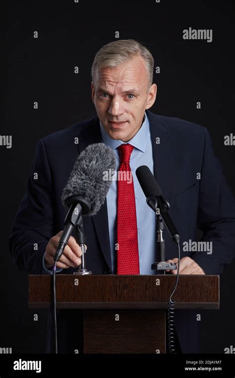 Vertical Portrait Of Mature Man Standing At Podium While Giving Speech