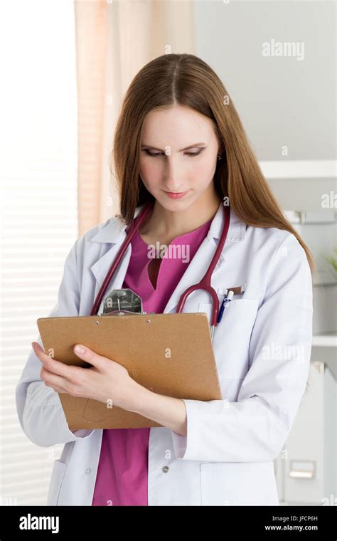 Portrait Of Young Female Doctor Holding Clipping Pad And Reading