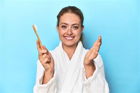 Premium Photo Blonde In Bathrobe With A Toothbrush In Blue Studio Receiving A Pleasant