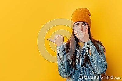 Shocked Woman In Hat Covers Mouth With Shock, Points Thumb To Side ...
