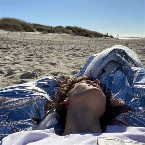 A Woman Laying On Top Of A Blue Tarp Covered Beach