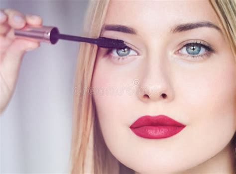 Woman Applying Mascara With Confidence Defined Brows And Red Lipstick Blonde Beauty Focused On