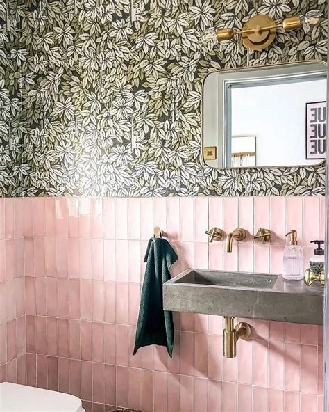 A Bathroom With Pink And Green Wallpaper Gold Faucet Sink And Mirror