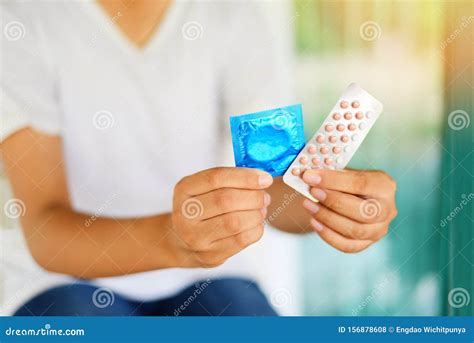 Young Woman Holding Contraception Pills And Condom In Hand Birth