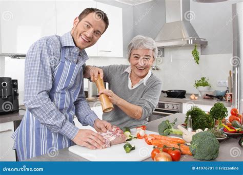 Young Man And Older Woman Cooking Together In The Kitchen Stock Image