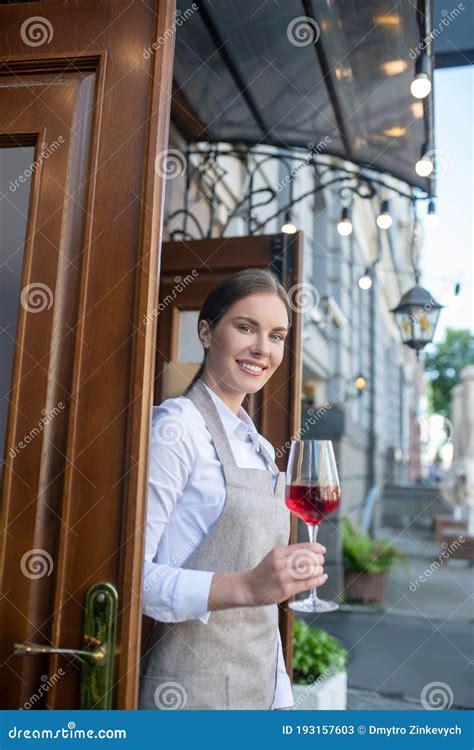 Smiling Cute Waitress In Grey Apron Holding Glass Of Wine Stock Image