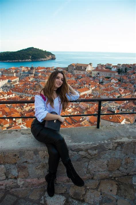 Attractive Brunette Influencer Sitting On The City Walls Of Dubrovnik Posing For A Vertical