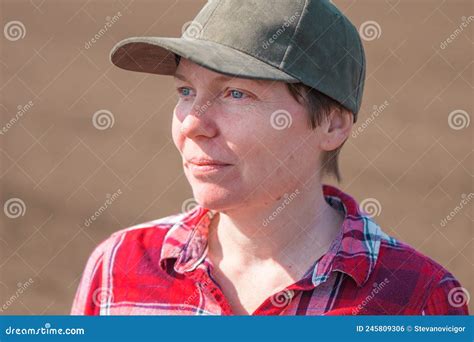 Female Farmer With Baseball Cap And Plaid Shirt Headshot Portrait