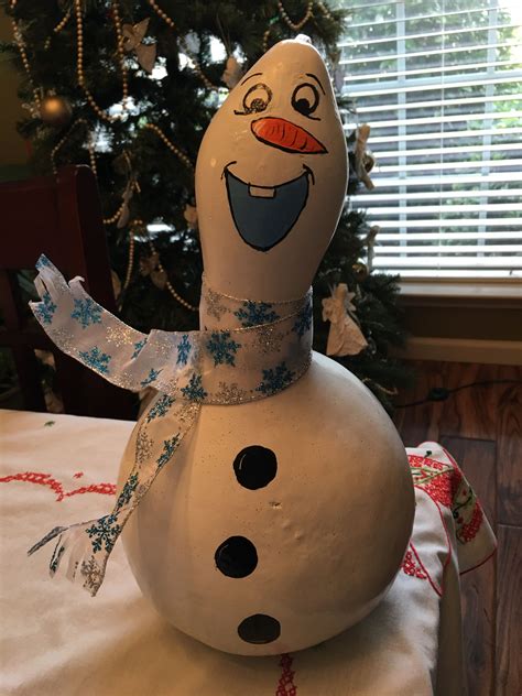 A Snowman Sitting On Top Of A Table Next To A Christmas Tree