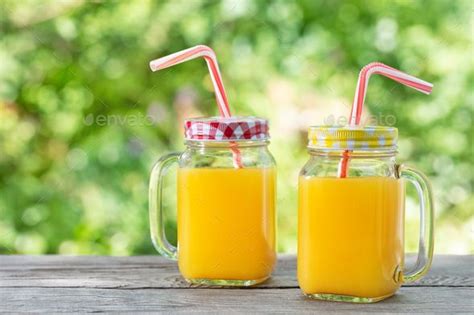 Orange Juice In Mason Jars With Straws On Wooden Table