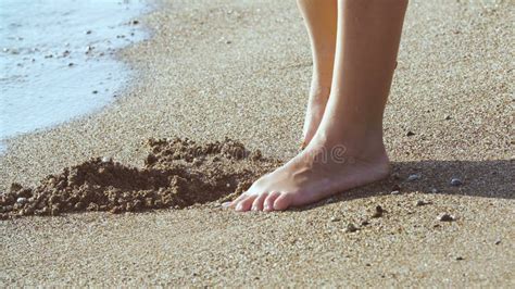 Tanned Female Legs On Beach Water Splashing On Feet In Ocean On Sandy