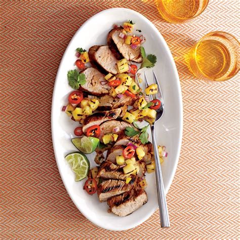 A White Plate Topped With Meat And Veggies Next To Two Glasses Of Beer