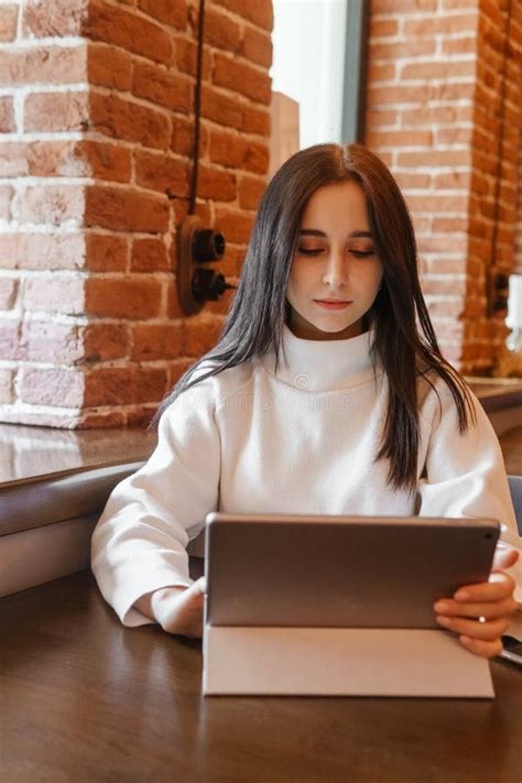 A Brunette Woman Is Working On A Tablet At A Table In A Cafe The Theme Of Freelancing And Free