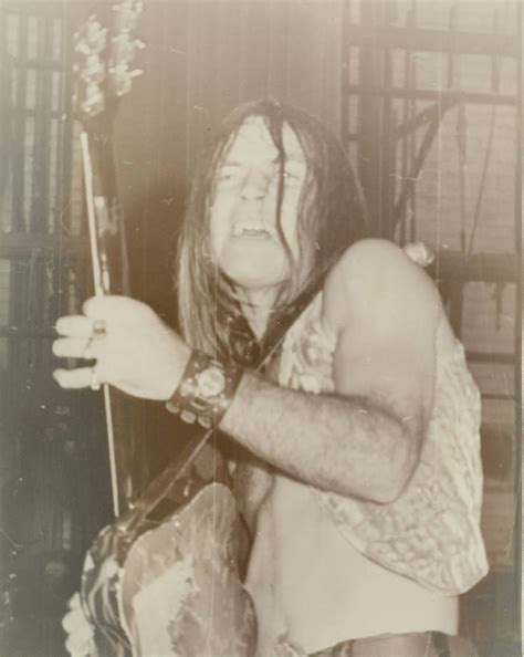 An Old Photo Of A Man With Long Hair Holding A Guitar In His Right Hand