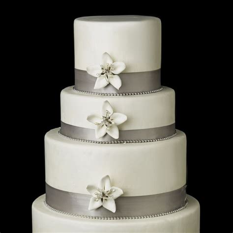 A Three Tiered Wedding Cake With White Flowers On The Top And Silver