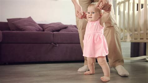 Baby learning walk. Father support daughter with first walk. Little kid ...