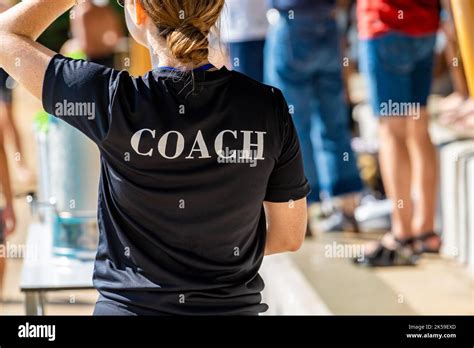 Back View Of Swimming Coaches Wearing Coach Shirt Working At An