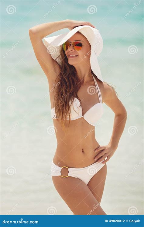 Woman In A White Bikini And Hat On A Tropical Beach Stock Photo