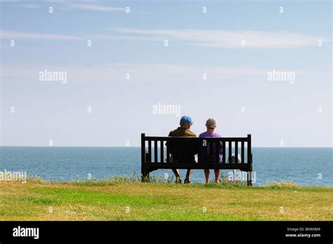 Vue Arrière Du Couple De Personnes âgées Assis Sur Banc De Falaise Face