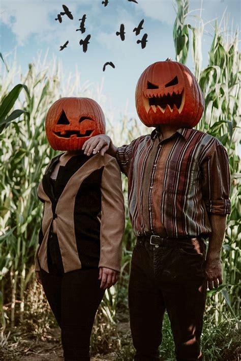 Two People Wearing Pumpkin Heads Standing Next To Each Other In Front