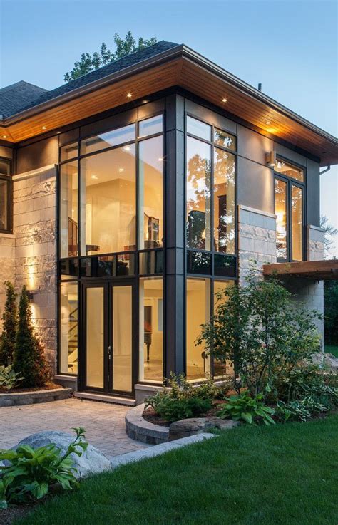 A Modern House With Glass Walls And Lots Of Windows In The Front Yard