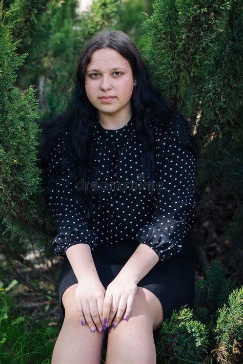 Brunette Teen Student Sitting In Schoolyard During School Day Wearing Black And White Dotted