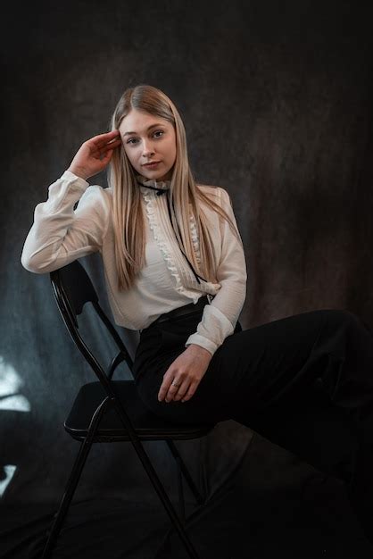 Premium Photo Portrait Of Seductive Blonde Caucasian Woman Sitting On Chair Isolated On Dark