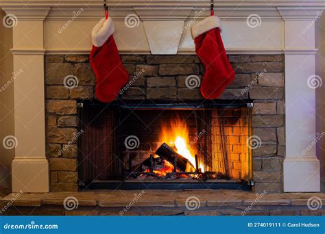 Two Red And White Christmas Stockings Hanging By A Blazing Fire For The