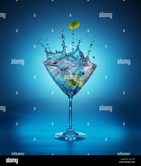 Martini Glass With Amazing Splash As The Result Of Olive Berries Falling Down In It Blue