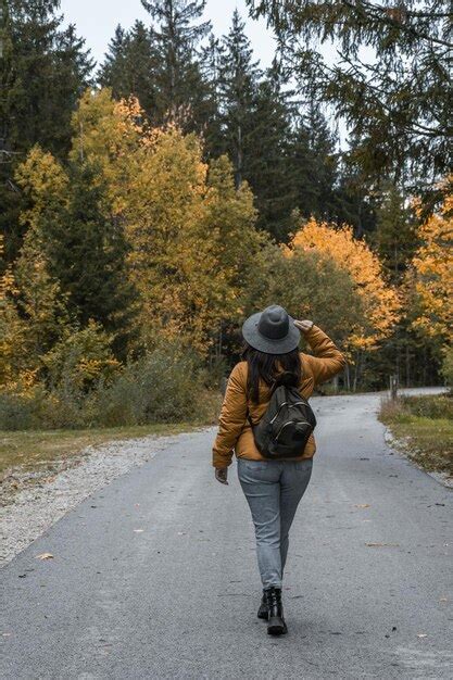 Vista traseira de mulher mochila caminhando na estrada através de