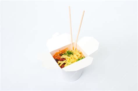 Рисовый вок с морепродуктами и овощами в белой коробке и деревянными ...