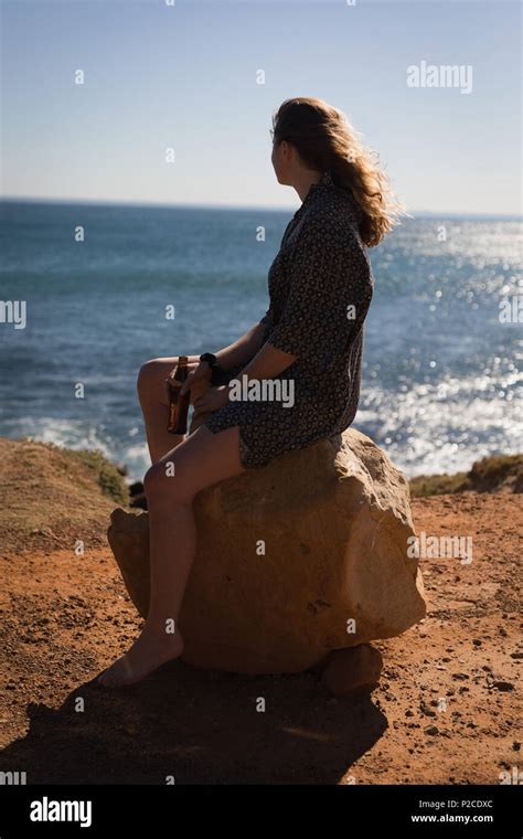 Woman sitting on a rock at beach Stock Photo - Alamy