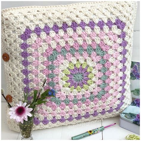 A Crocheted Granny Blanket With Flowers In The Vase And Other Items