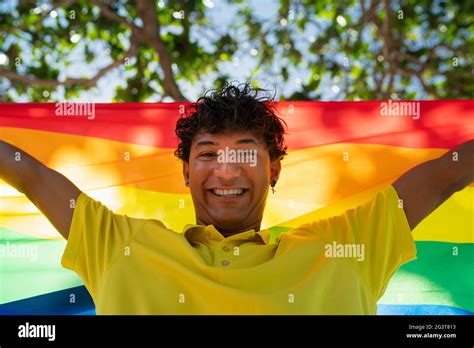 Le jeune homme gay tient fièrement le drapeau lgbt entre ses mains devant la mer inclusive