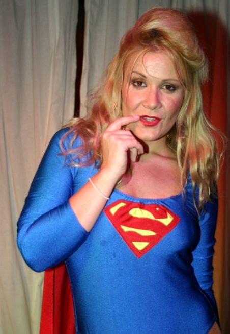 A Woman In A Superman Costume Posing For The Camera With Her Finger On