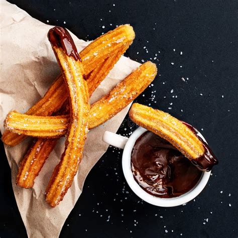 Churros With Sugar Dipped In Chocolate Sauce On A Black Background