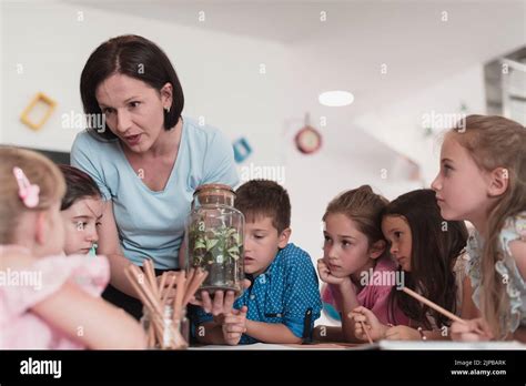 Female Teacher With Kids In Biology Class At Elementary School