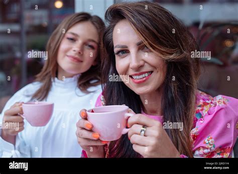 Excited Cheerful Smiling Mother And Daughter Drinking Coffee In