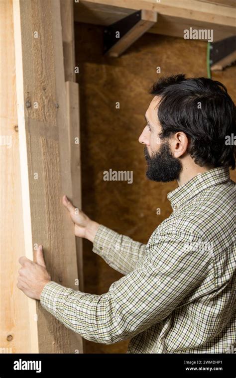 Vertical Photo Concentrated Carpenter Sorts Through Planks Of Wood