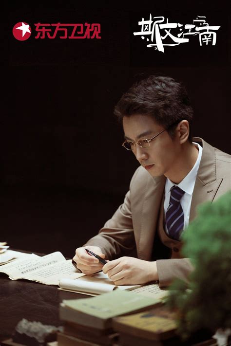 A Man Sitting At A Desk Writing On A Piece Of Paper With An Ink Pen In