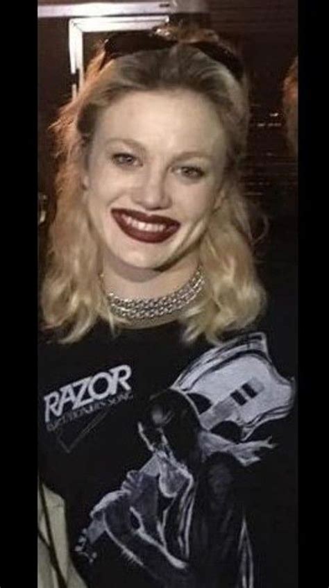 a woman wearing a black shirt and smiling at the camera with red lipstick on her lips