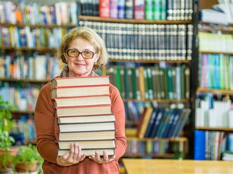 Download Elderly Librarian Holding A Book Wallpaper | Wallpapers.com